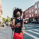 Frau mit Mund-Nasen-Bedeckung und Smartphone