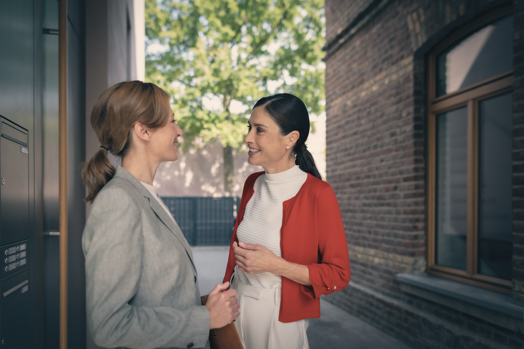 2 Frauen unterhalten sich vor dem Eingangsbereich eines Gebäudes